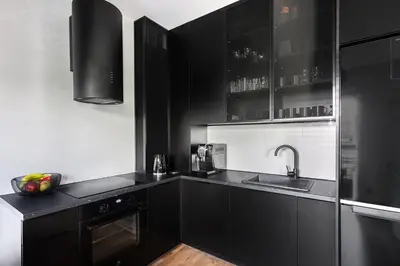 a kitchen with black cabinets and a sink at Victoria Apartment in Kraków