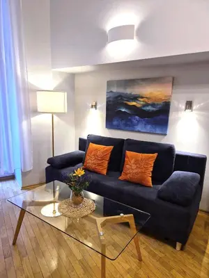 a living room with a blue couch and a glass table at Ariadna - Pantheon Apartments in Kraków