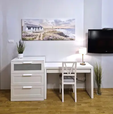 a white desk with a chair and a painting on the wall at Ariadna - Pantheon Apartments in Kraków