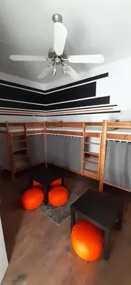 a living room with a ceiling fan and orange pillows at Kraków Chilli Hostel in Kraków