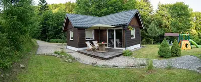 a small cabin in a yard with a playground at RESETówka nr 2 - domek rodzinny na odludziu in Jaszczurowa
