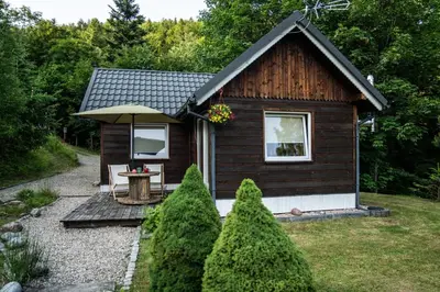 a small cabin with a table and an umbrella at RESETówka nr 2 - domek rodzinny na odludziu in Jaszczurowa