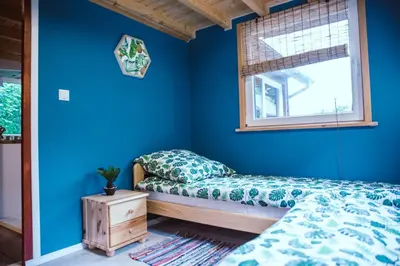 a bedroom with blue walls and a bed and a window at RESETówka nr 2 - domek rodzinny na odludziu in Jaszczurowa