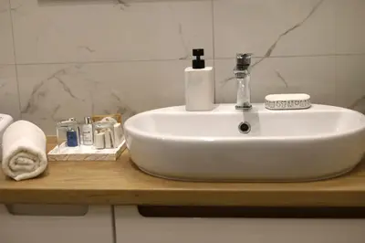 a white sink on a wooden counter in a bathroom at Apartament LUX in Zator