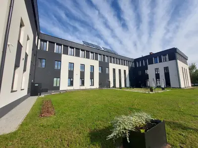 a large building with a grass field in front of it at VANTA Business Center in Skawina
