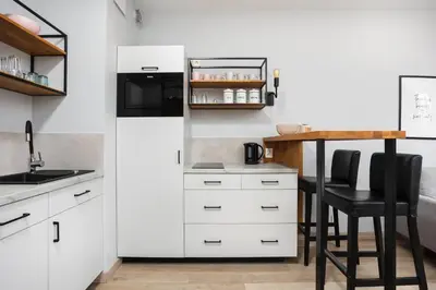 a kitchen with white cabinets and a table and chairs at City of the Kings-Alice Apartment in Kraków