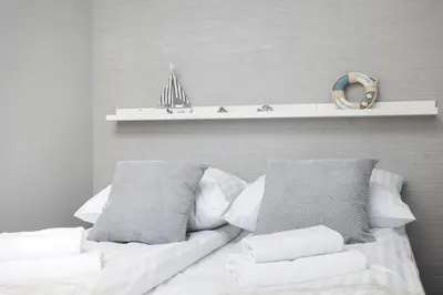 a white bed with white pillows and a shelf at City of the Kings-Alice Apartment in Kraków