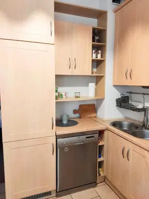 a small kitchen with wooden cabinets and a dishwasher at *** Cozy and bright apartment (over 50m2) *** in Kraków