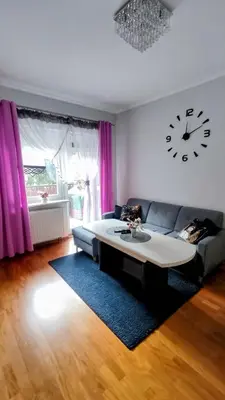 a living room with a couch and a clock on the wall at *** Cozy and bright apartment (over 50m2) *** in Kraków