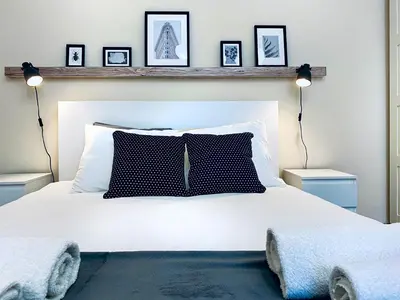 a bedroom with a white bed with three pictures on the wall at Cozy Apartment in the heart of Cracow, Jewish District in Kraków