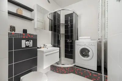 a bathroom with a washing machine and a washer at Lea Apartments Kraków Krowodrza by Noclegi Renters in Kraków