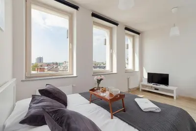 a bedroom with a bed with a table and windows at Lea Apartments Kraków Krowodrza by Noclegi Renters in Kraków
