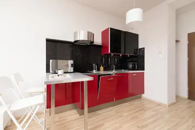 a kitchen with red cabinets and a white counter at Lea Apartments Kraków Krowodrza by Noclegi Renters in Kraków