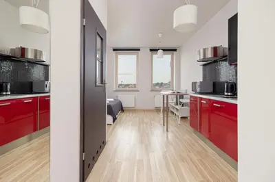 a kitchen with red cabinets and a dining room at Lea Apartments Kraków Krowodrza by Noclegi Renters in Kraków