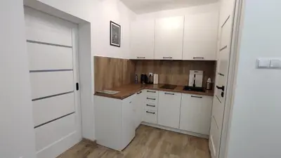 a kitchen with white cabinets and a wooden floor at Apartamenty AgPa7 in Zator