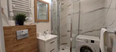 a bathroom with a sink and a washing machine at Apartamenty AgPa7 in Zator