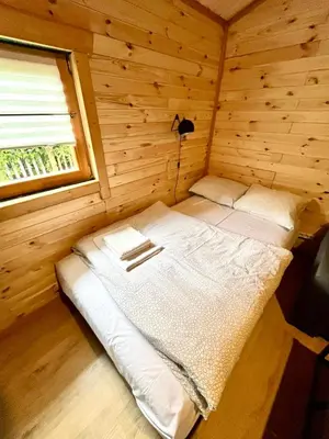 a small bed in a wooden room with a window at Domek drewniany in Podzamcze