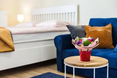 a living room with a blue couch and a red cup with flowers at Vintage Sebastiana Apartment in Kraków