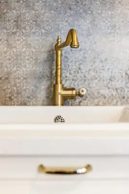 a sink with a gold faucet on top of it at Vintage Sebastiana Apartment in Kraków