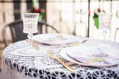 a table with a white lace table cloth and plates and glasses at Vintage Sebastiana Apartment in Kraków