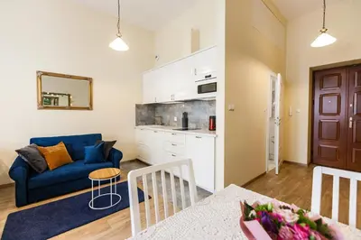 a living room with a blue couch and a kitchen at Vintage Sebastiana Apartment in Kraków