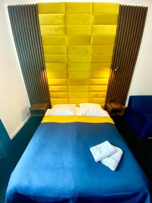 a bedroom with a blue bed with a yellow headboard at Old Town Gertrudy Apartment - Topolove Rooms & Apartments in Kraków