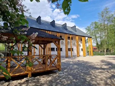 a large white building with a gambrel roof at Skansen Forest in Liszki