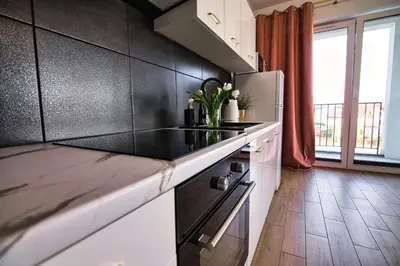 a living room with a green couch and a table with flowers at Apartament The Palm 35 by Housine in Zator