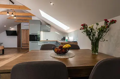 a kitchen and dining room with a wooden table with a bowl of fruit at Bianco Apartamenty Laskowa - Zator in Zator