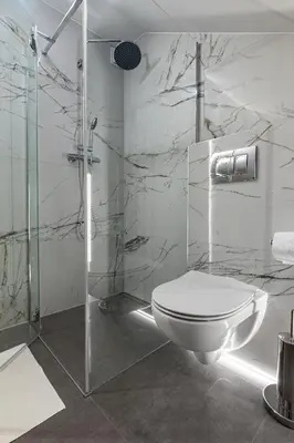 a bathroom with a toilet and a glass shower at Bianco Apartamenty Laskowa - Zator in Zator
