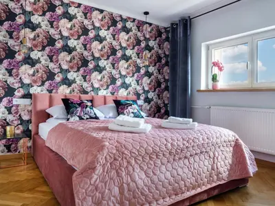 a bedroom with a pink bed with a floral wall at CracWoW City Center Apartment in Kraków