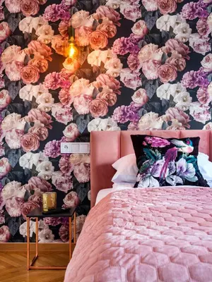a bedroom with a pink bed and a floral wall at CracWoW City Center Apartment in Kraków