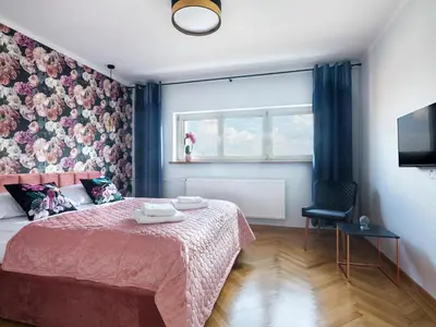 a bedroom with a pink bed and a window at CracWoW City Center Apartment in Kraków