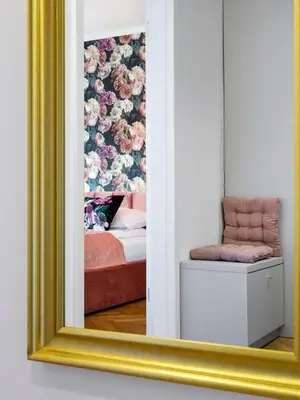 a mirror reflecting a bedroom with a bed and a chair at CracWoW City Center Apartment in Kraków