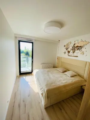 a bedroom with a large bed in a room with a window at Luxury White Apartment in Park Lotników in Kraków