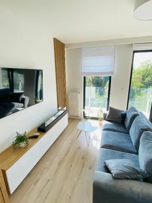 a living room with a blue couch and a tv at Luxury White Apartment in Park Lotników in Kraków