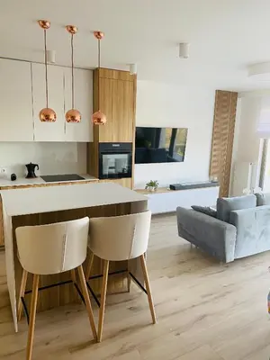 a kitchen and living room with a table and chairs at Luxury White Apartment in Park Lotników in Kraków