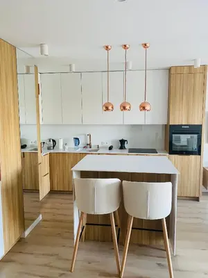 a kitchen with a table and two white chairs at Luxury White Apartment in Park Lotników in Kraków