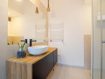 a bathroom with a white bowl sink on a wooden counter at Apartament Bocheńska in Kraków