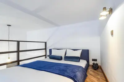 a bedroom with a bed with blue and white pillows at Aparts Jablonowskich in Kraków