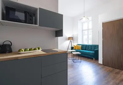 a kitchen and living room with a blue couch at Aparts Jablonowskich in Kraków