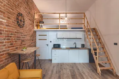 a loft kitchen with a staircase and a brick wall at Aparts Jablonowskich in Kraków