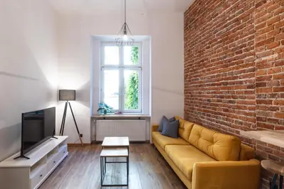a living room with a couch and a brick wall at Aparts Jablonowskich in Kraków