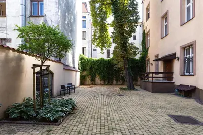 an empty courtyard with trees and plants and buildings at Aparts Jablonowskich in Kraków