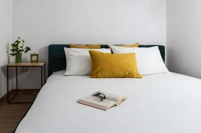 a white bed with a book and a pair of scissors on it at Aparts Jablonowskich in Kraków