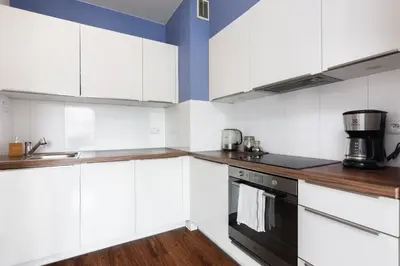 a kitchen with white cabinets and a black appliance at Pawia Apartments Modern 2 in Kraków