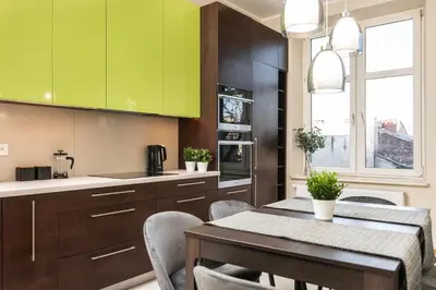 a kitchen with green cabinets and a table with chairs at Spacious Apartment Around The Food Market - 5' to the Market Square - by Upstairs in Kraków