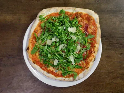a pizza sitting on a white plate on a table at Suite Loft in Zabierzów