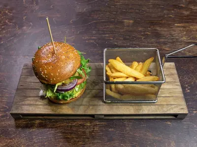 a hamburger and french fries on a wooden tray at Suite Loft in Zabierzów