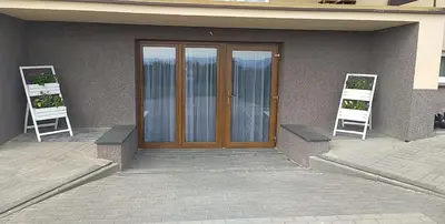 two white chairs standing next to a wooden door at Apartament Anna in Bachowice